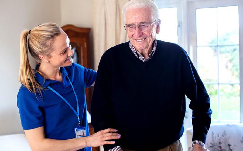 Frau stützt alten Mann in seinem zu hause