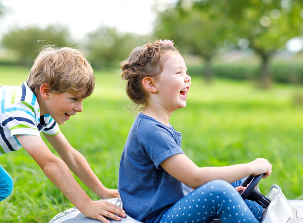 2 Kinder auf einem Bobbicar