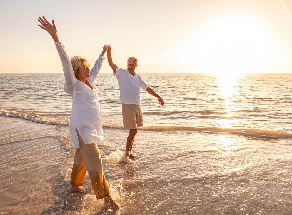 Seniorenpaar läuft im Meer am Strand
